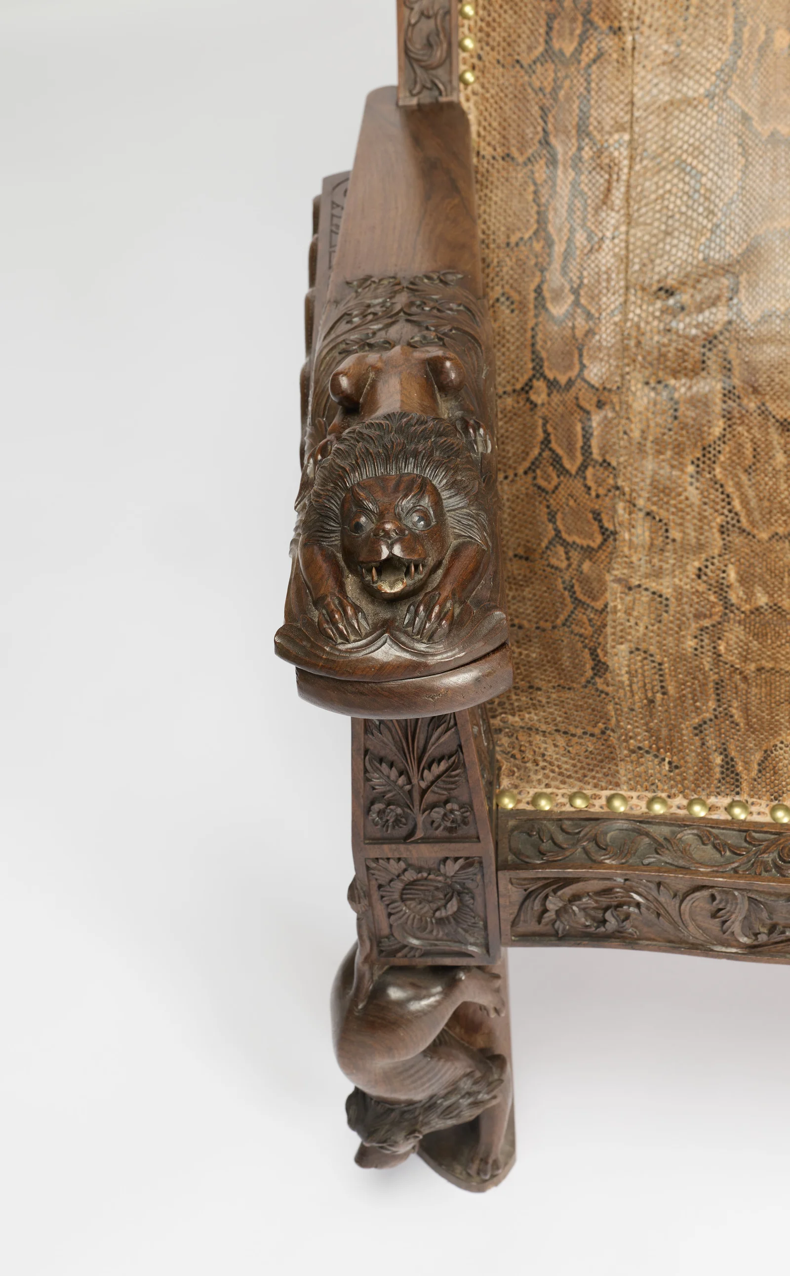 The couched lion bares its teeth over outstretched claws, the tapering support below panelled with leaves and flowerheads.