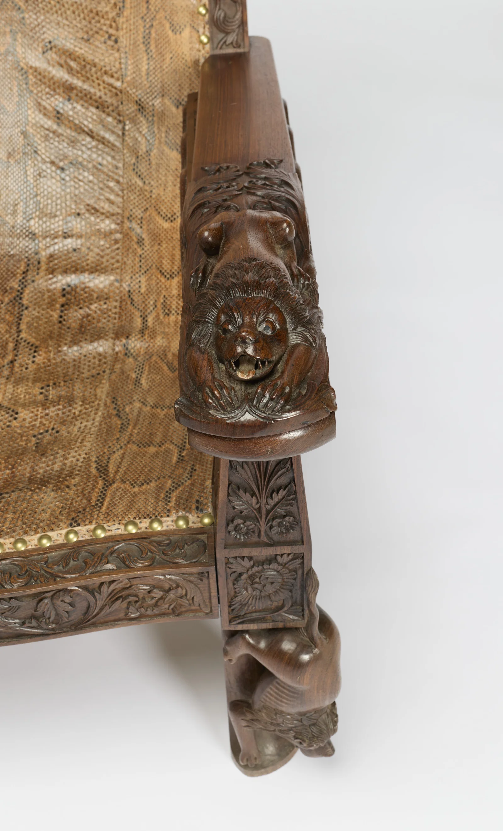 Seen from above, the lion crouches at the end of the arm, the seat rail beyond carved with paired birds among foliage.