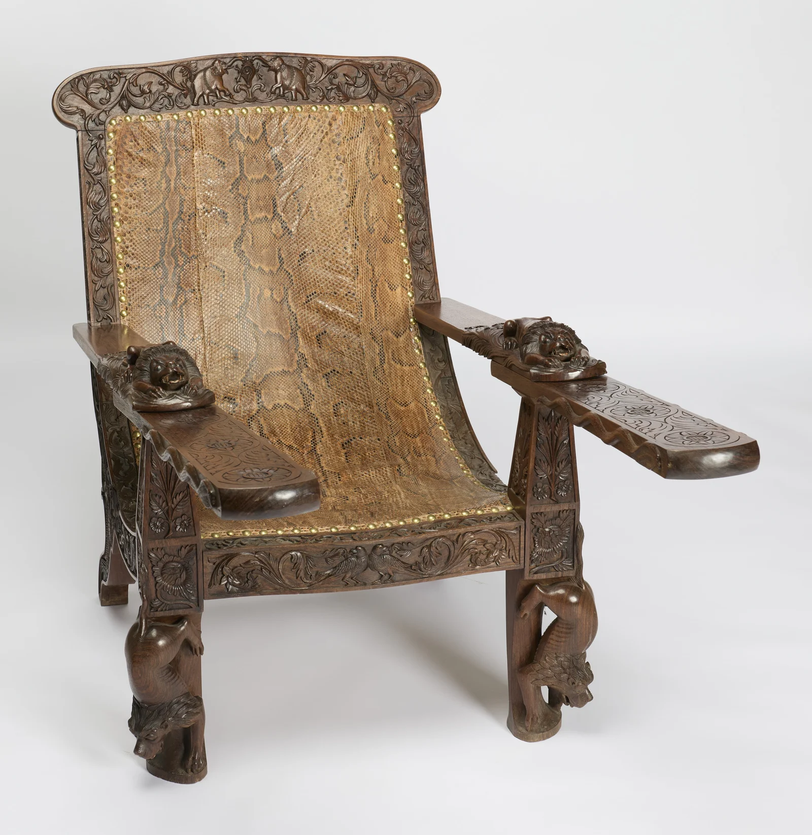 Both boards swing forward from beneath the arms, their tops incised with flowerhead roundels, the carved beasts descending the front legs below.