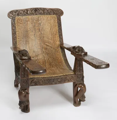 Both boards swing forward from beneath the arms, their tops incised with flowerhead roundels, the carved beasts descending the front legs below.