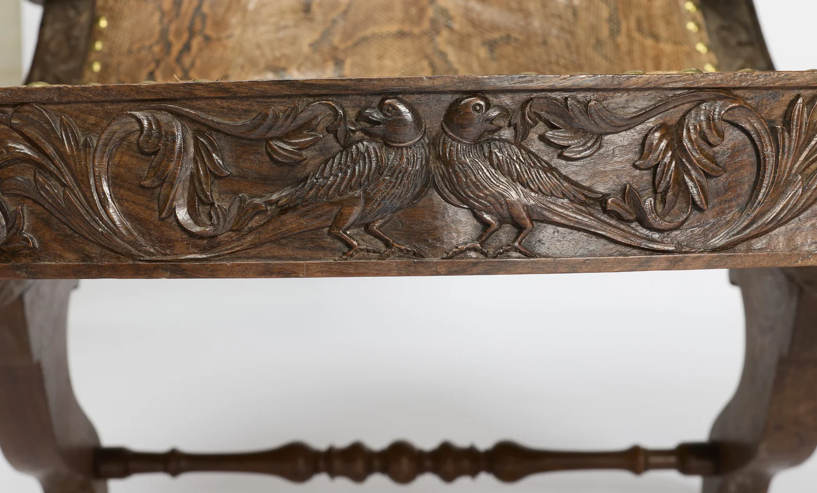 A pair of confronted birds among acanthus scrolls runs across the front rail, the turned stretcher crossing below.