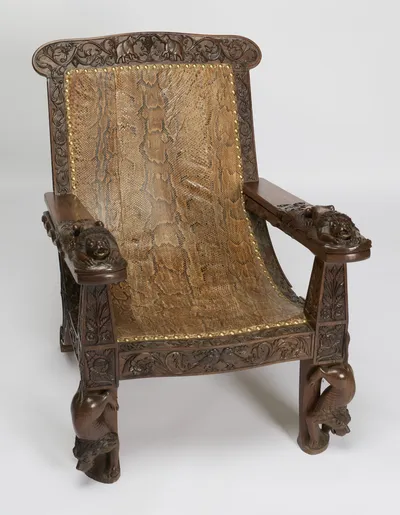The leg rests folded back beneath the arms, showing the tapering arm supports panelled with leaves and flowerheads.