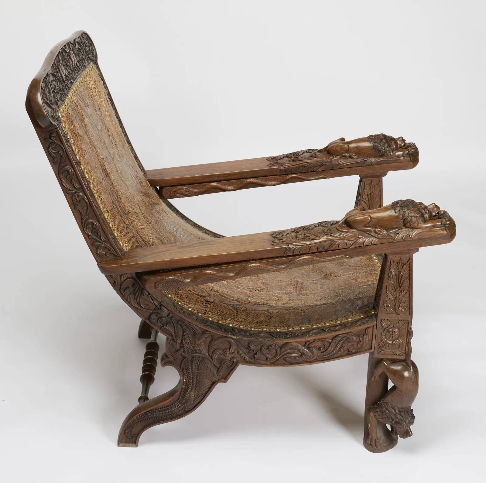 The seat sweeps down in a deep curve between scrolled rear legs and figural front legs, a carved snake rippling along the edge of each folded board.