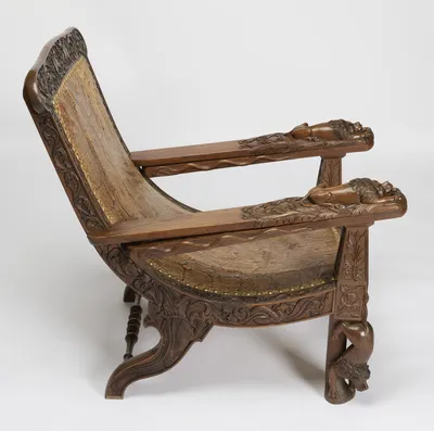 The seat sweeps down in a deep curve between scrolled rear legs and figural front legs, a carved snake rippling along the edge of each folded board.