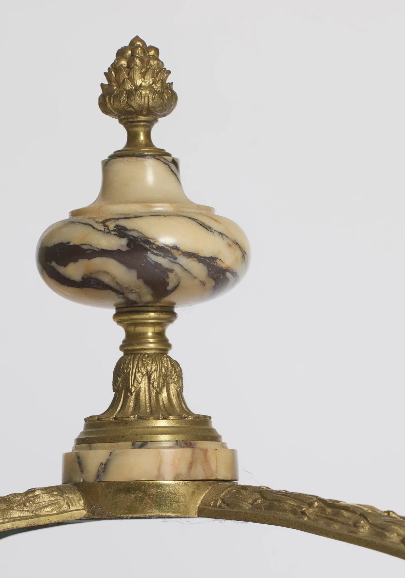 A veined marble knop held between gilt collars and crowned with a cast pinecone.