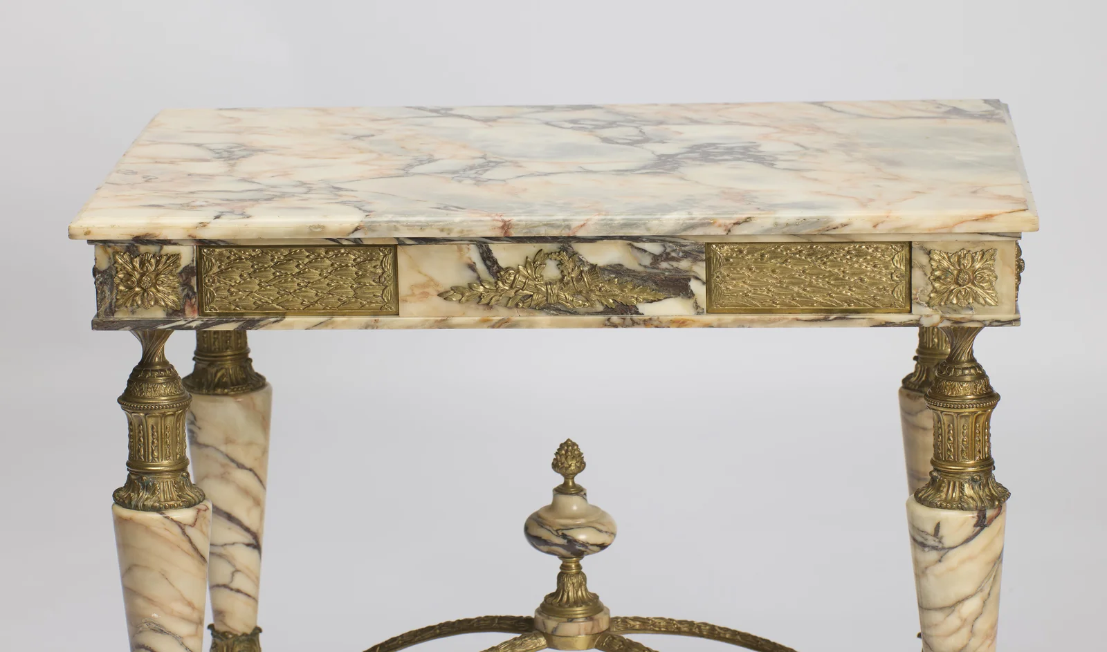 Grey, rust and blush veining running across the slab above the full run of gilt panels and the finial below.