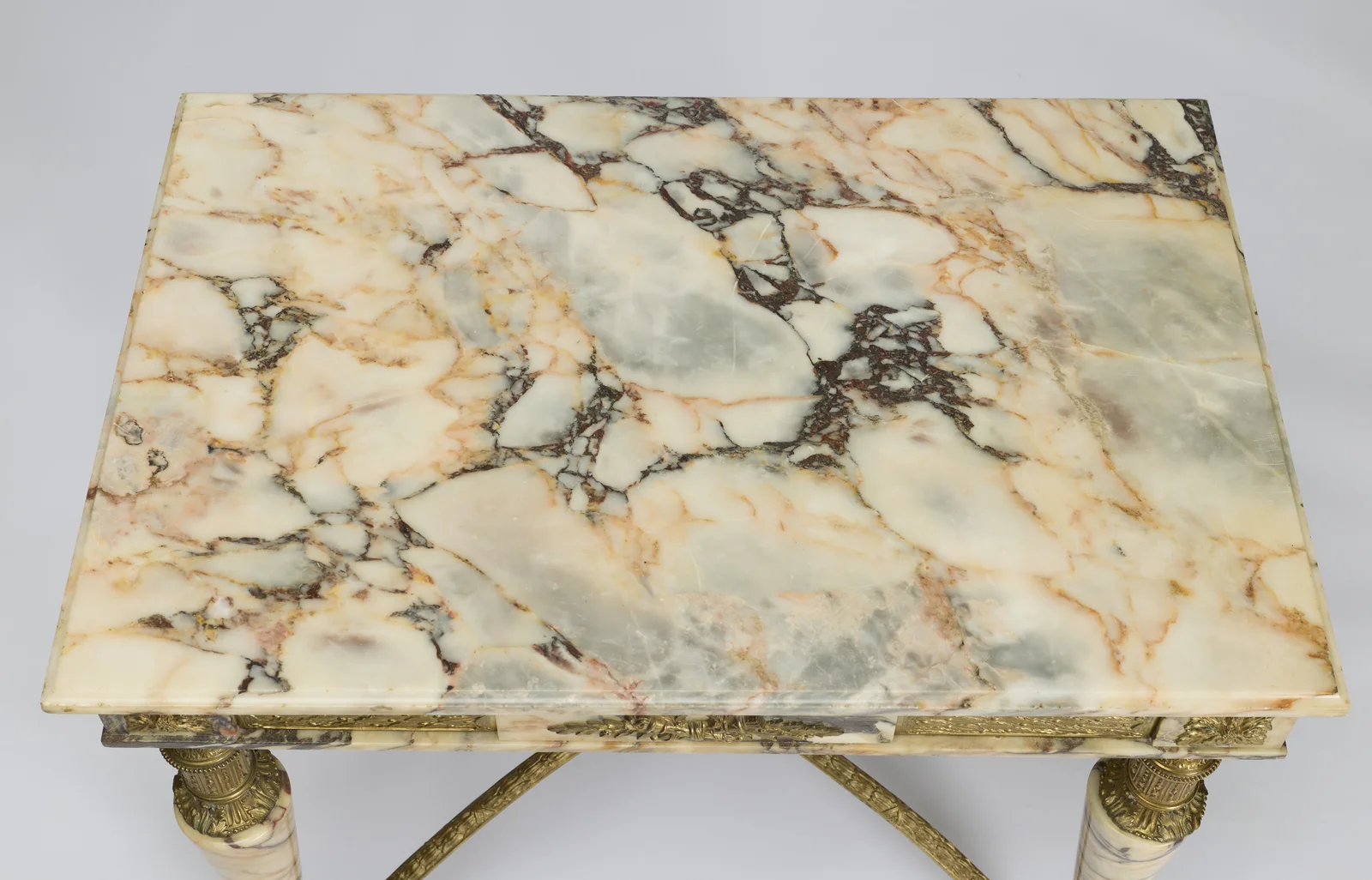 A cream ground broken by grey, rust and blush veins, the edge cut with a shallow bevel.