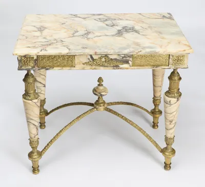 The complete table with the veined slab in view above the mounted frieze and all four splayed gilt legs.