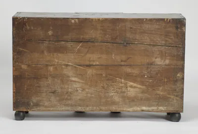 Plain boards run the full width of the back, scuffed and marked with age, over ebonised ball feet.