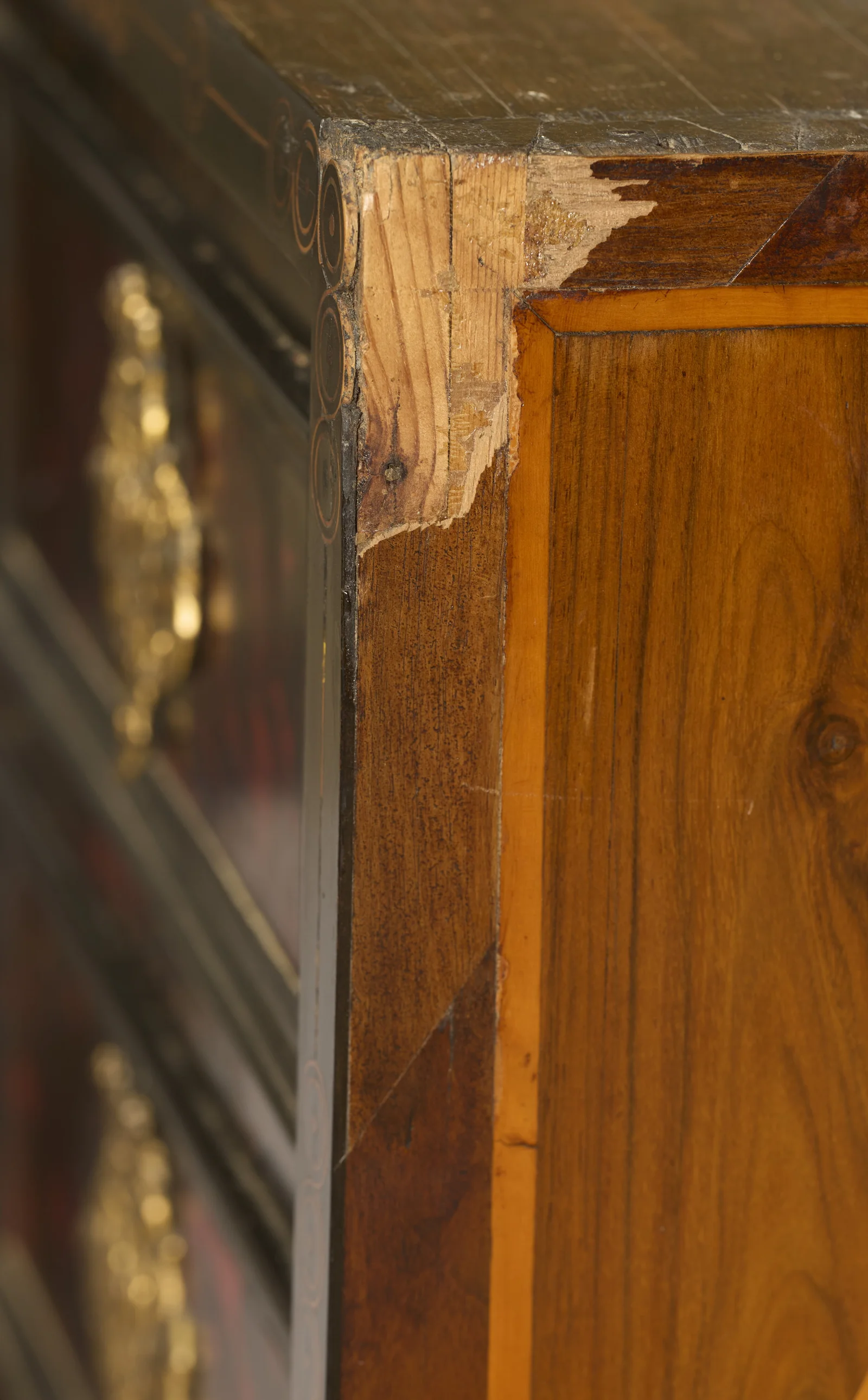 Veneer is chipped away at the corner exposing pale timber beneath, with scratching across the top surface.