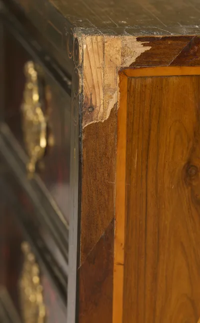 Veneer is chipped away at the corner exposing pale timber beneath, with scratching across the top surface.