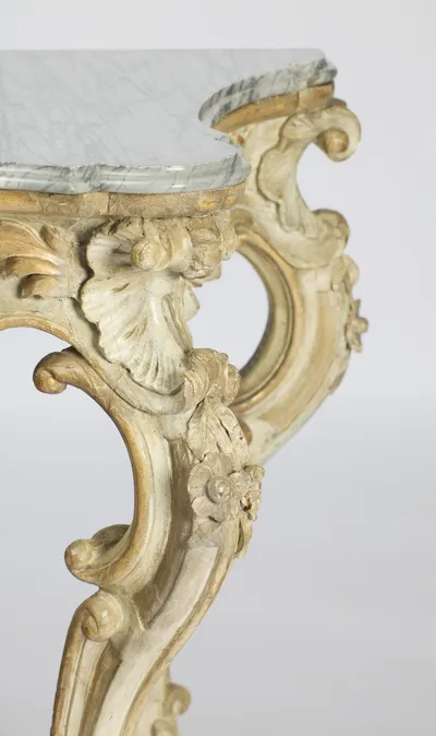 One front corner showing the moulded marble edge, a carved shell at the knee and a flower rosette on the leg below.