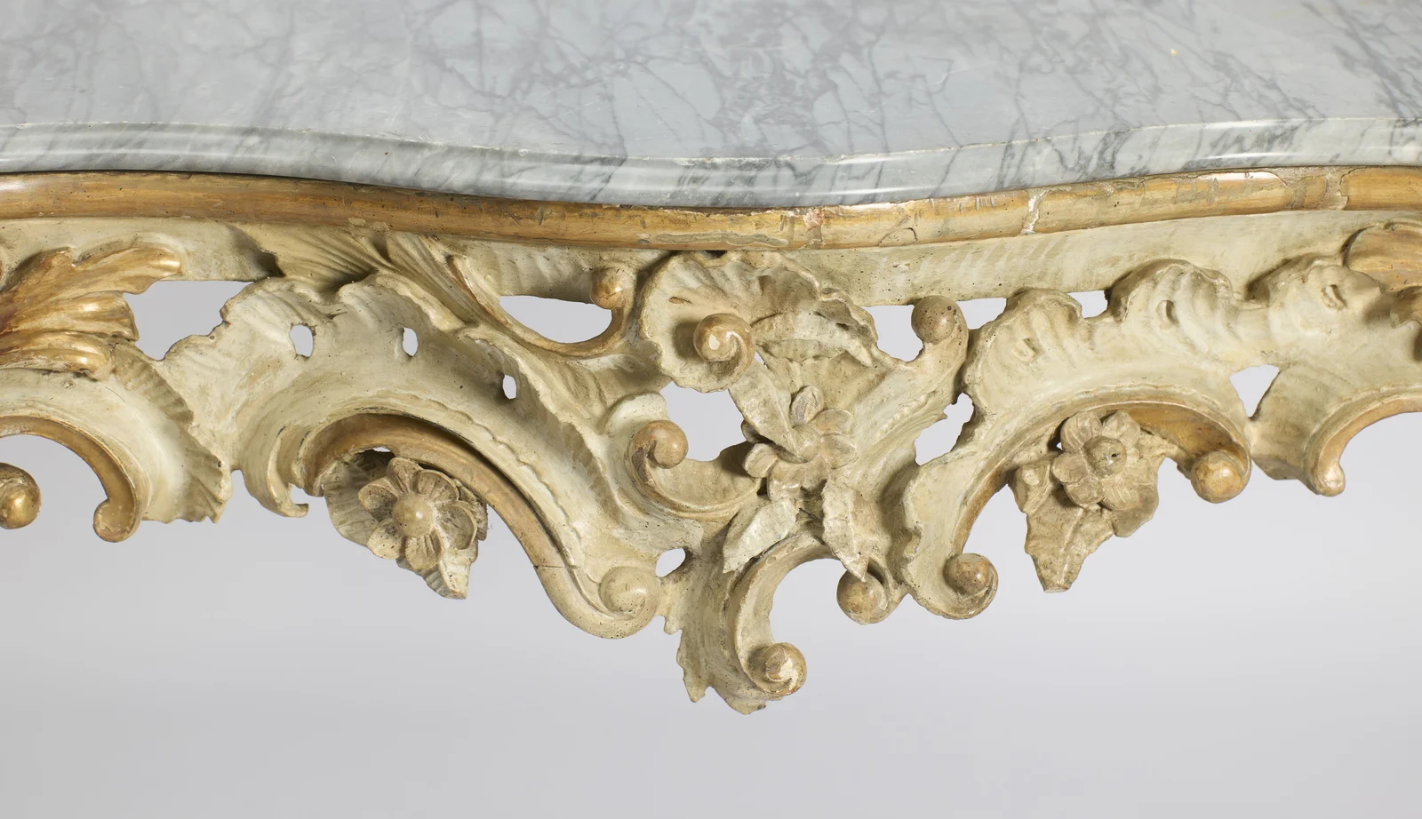 The moulded marble edge above a gilt fillet, with the pierced apron of scrolling leafage and carved flowerheads below.