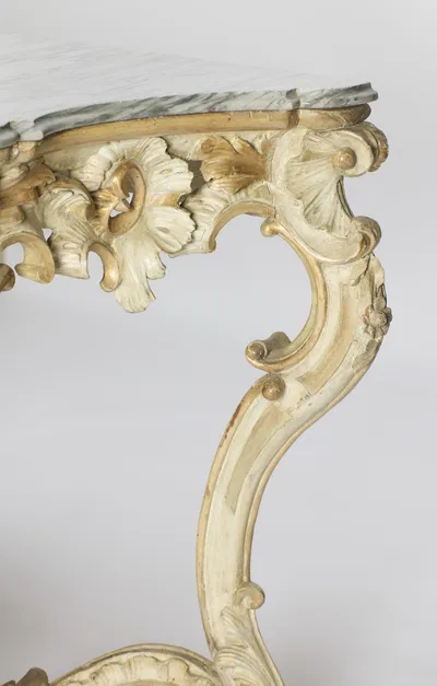 Profile of a front leg showing the pierced carving above and the gilt panel running down the curve of the leg.