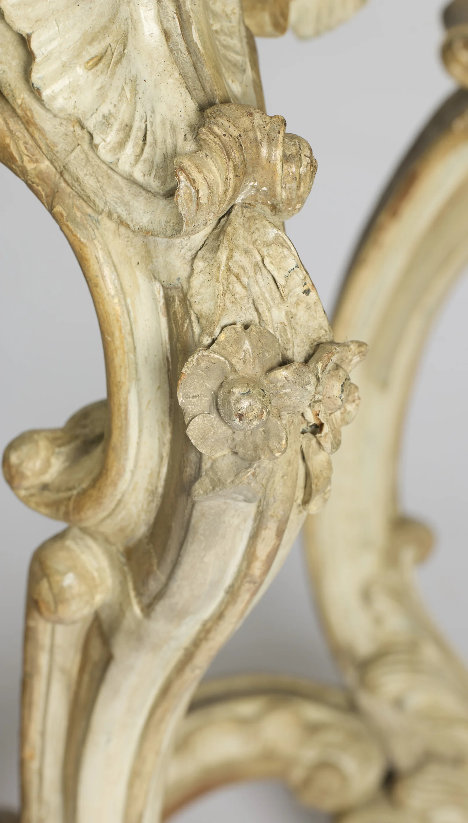 Close-up of the two carved rosettes applied where the scrolls meet on the leg, with old chips visible to the petals.