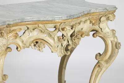 Close angled view showing how deeply the apron is undercut, with rubbed gilt highlights against the cream paint.