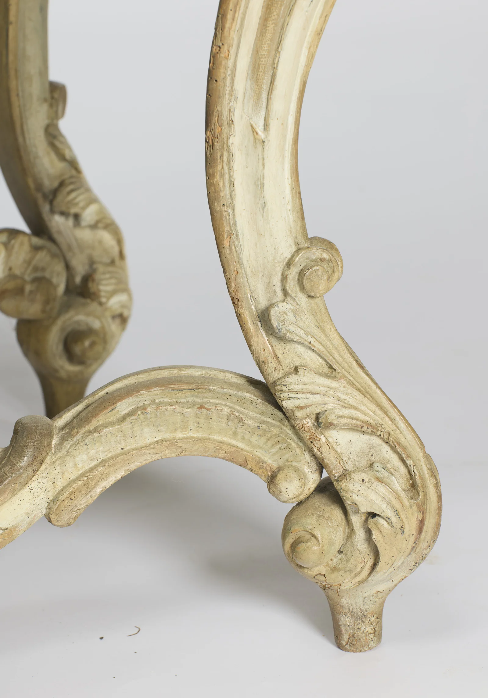 A front scroll foot with the ribbed stretcher curving behind, the paint worn through on the high points.