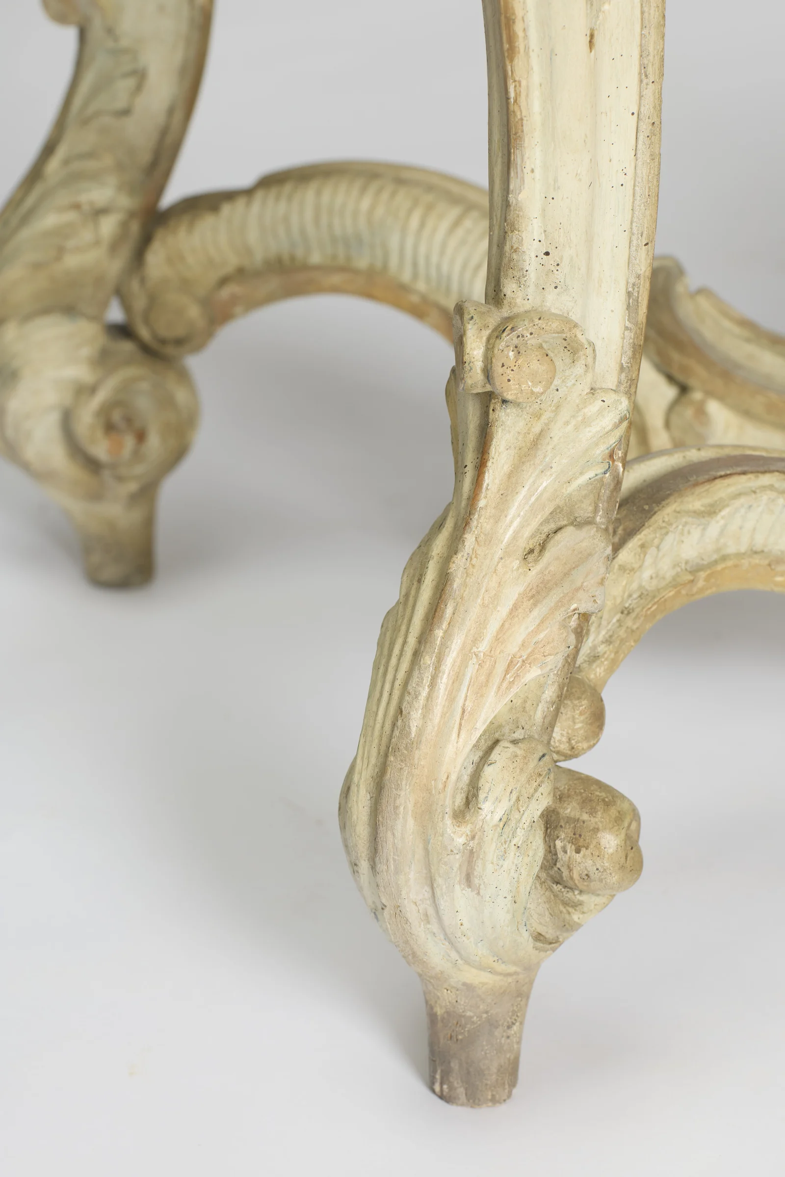 Front and rear feet together with the stretcher rising between them, the leaf-wrapped scrolls showing rubbed paint and small losses.