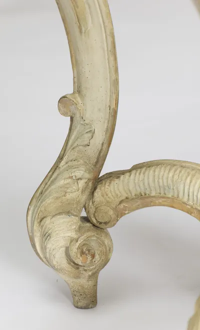 A single scroll foot with a small leaf spur above it and the coiled end of the stretcher meeting it from the side.