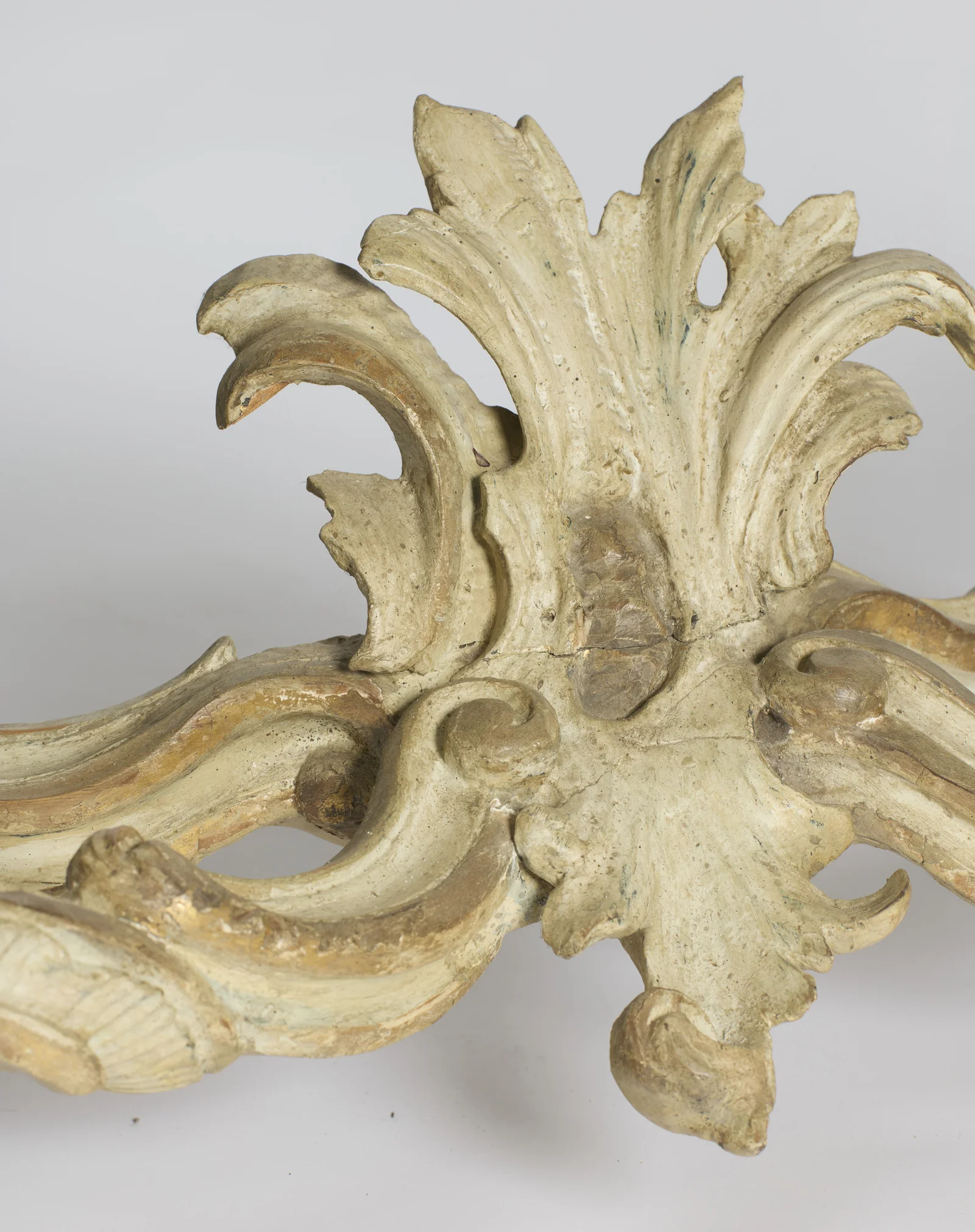 Close view of the acanthus plume at the centre of the stretcher, showing an old crack running across its base.