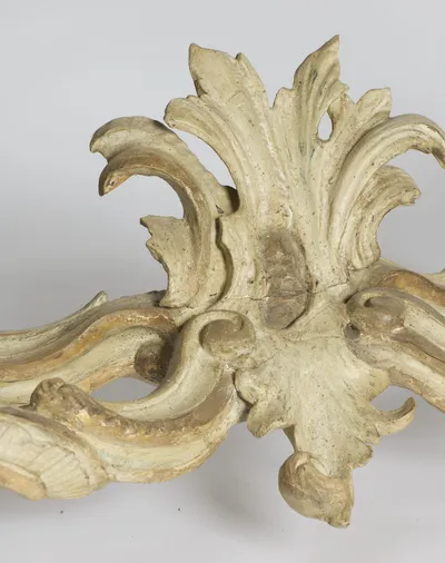 Close view of the acanthus plume at the centre of the stretcher, showing an old crack running across its base.