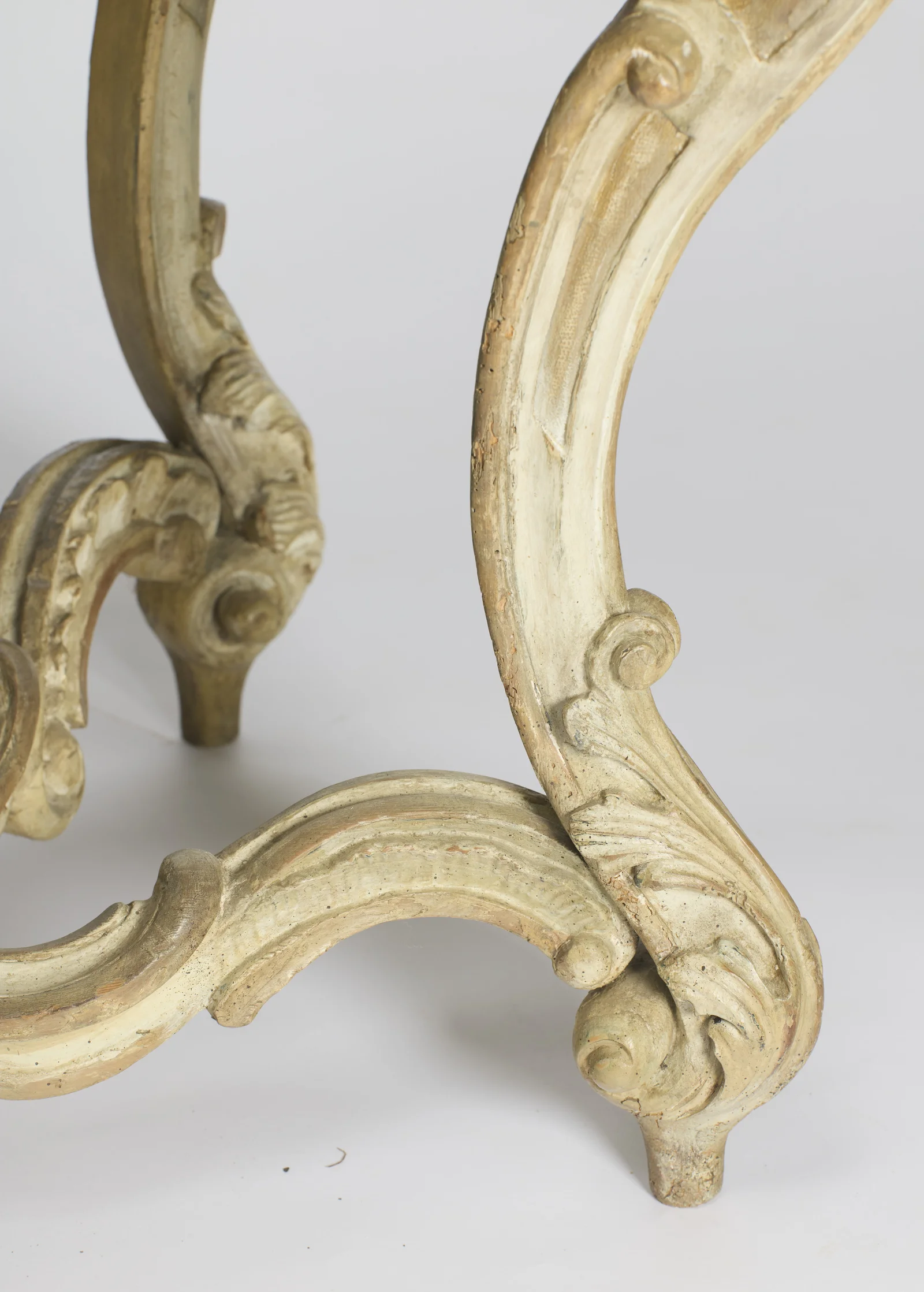 The junction where the scrolled end of the stretcher meets the leg above the foot, wrapped with carved leafage.