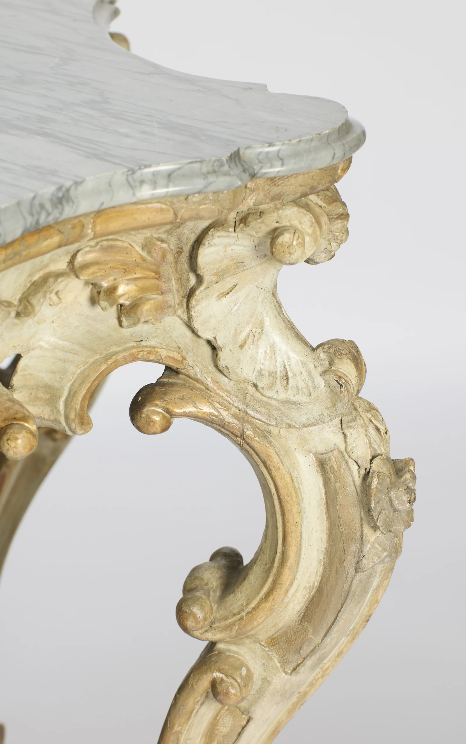 The fan-shaped shell at the top of one leg with gilt scrolls around it and an applied rosette on the knee.