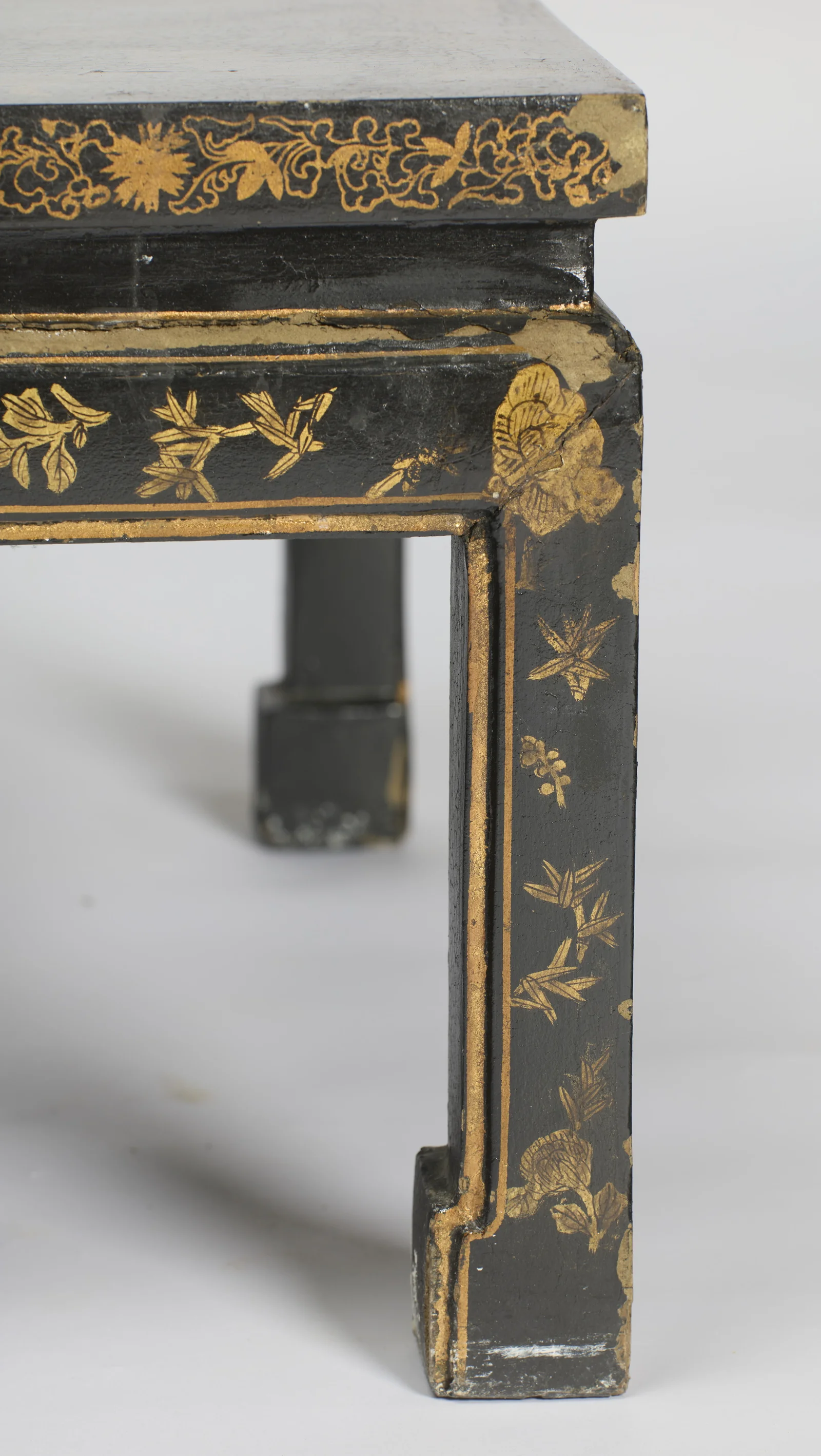 The gilt-lined panel of sprigs running down the leg to the scrolled block foot, with losses where the leg meets the apron.