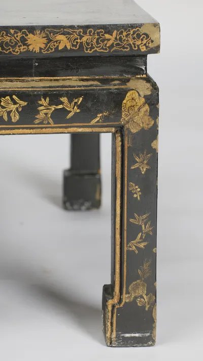The gilt-lined panel of sprigs running down the leg to the scrolled block foot, with losses where the leg meets the apron.