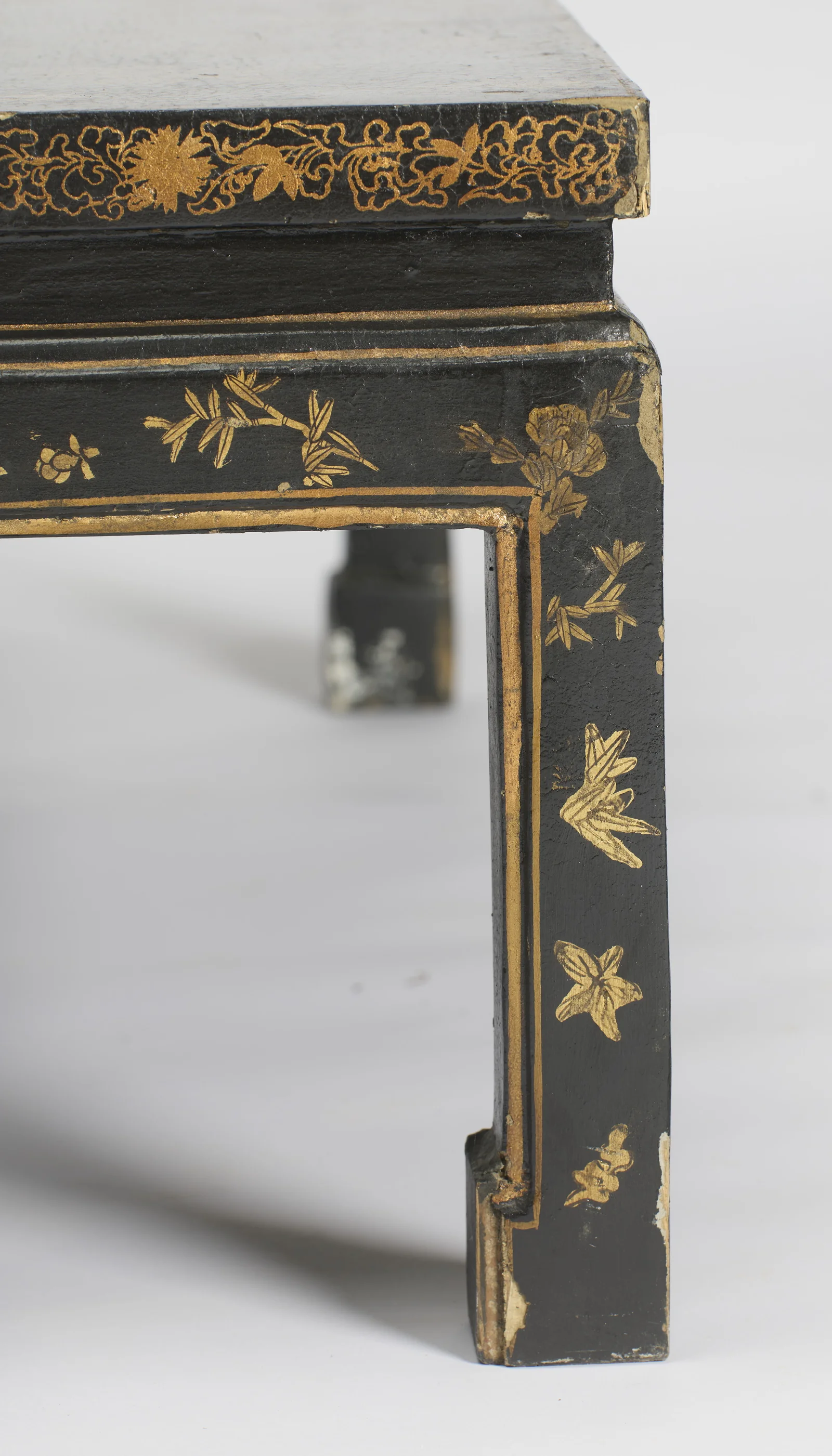 Flower heads and leaf sprigs inside the gilt border of the leg, with wear and small losses at the foot.