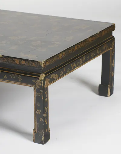 The border of scrolling foliage along the top edge, with fine cracking to the black surface of the top and chips at the corner.