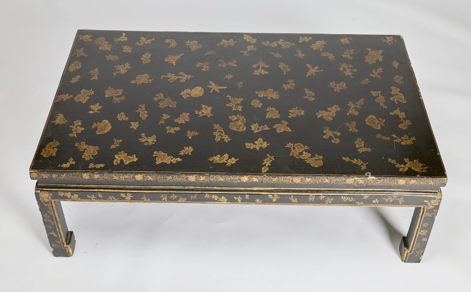 Gilt flower sprays and leafy sprigs scattered over the black ground, with butterflies and a dragonfly among them, all within a single gilt line border.