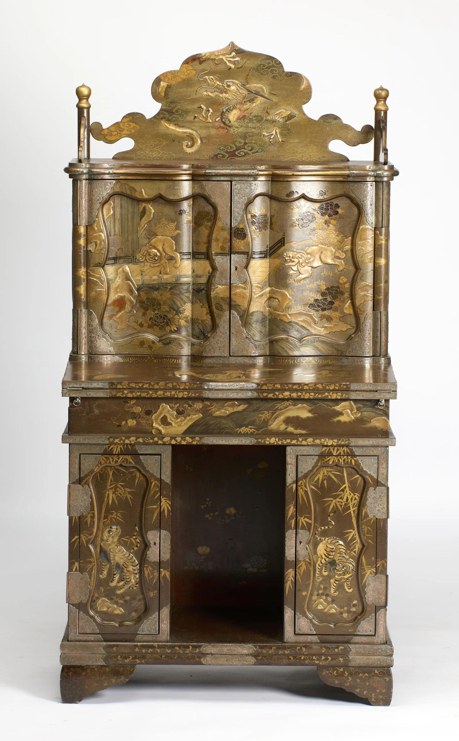 The cabinet closed, the dragon crest above serpentine lion-decorated doors, the fall-front below, and tiger doors flanking the open kneehole on shaped bracket feet.