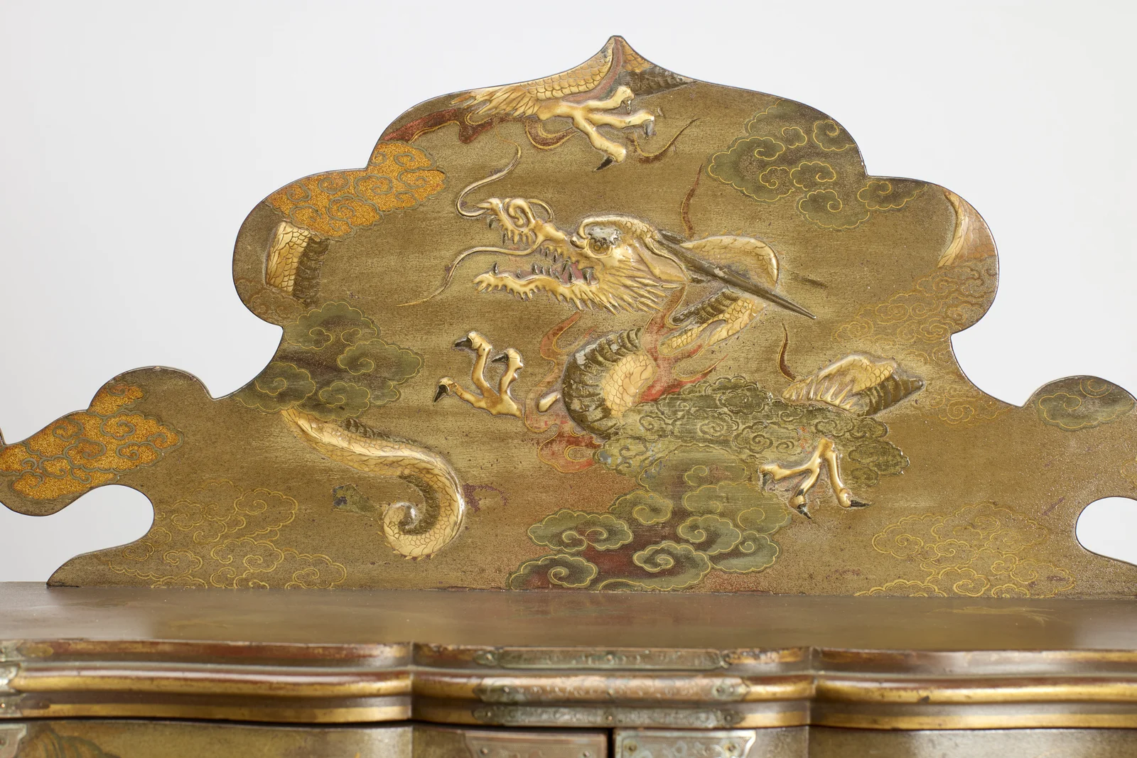 The shaped cresting decorated in raised gold and silver tones with a dragon coiling through clouds, between gilt ball finials.
