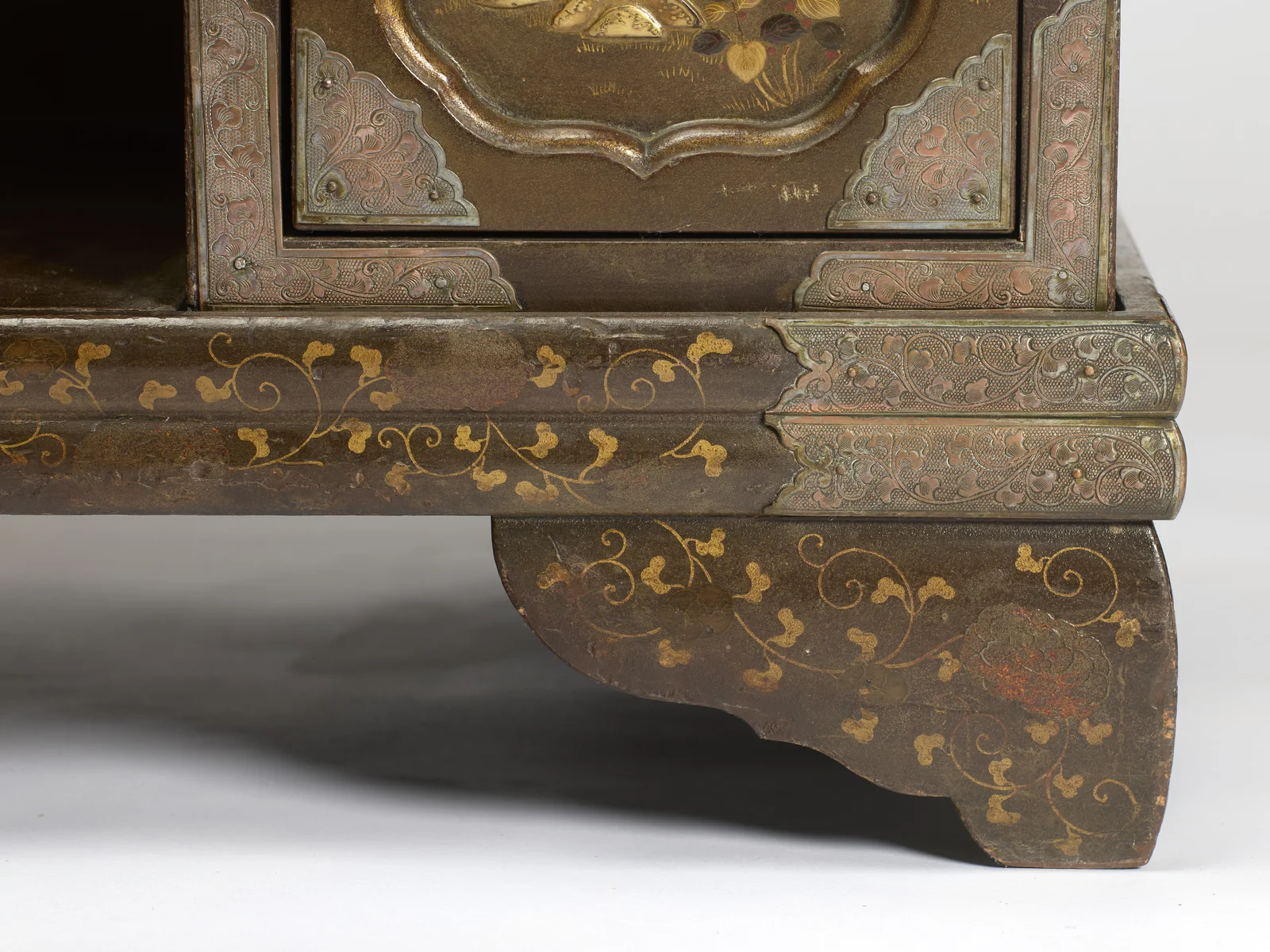 The moulded plinth edged with engraved metal, trailing gilt vines running down onto the shaped bracket foot.