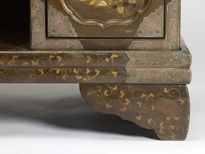 The moulded plinth edged with engraved metal, trailing gilt vines running down onto the shaped bracket foot.
