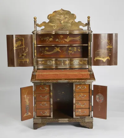 Upper doors, fall-front and lower doors all open, revealing the red-lacquered interior, the fabric-lined writing surface and twin banks of four drawers.