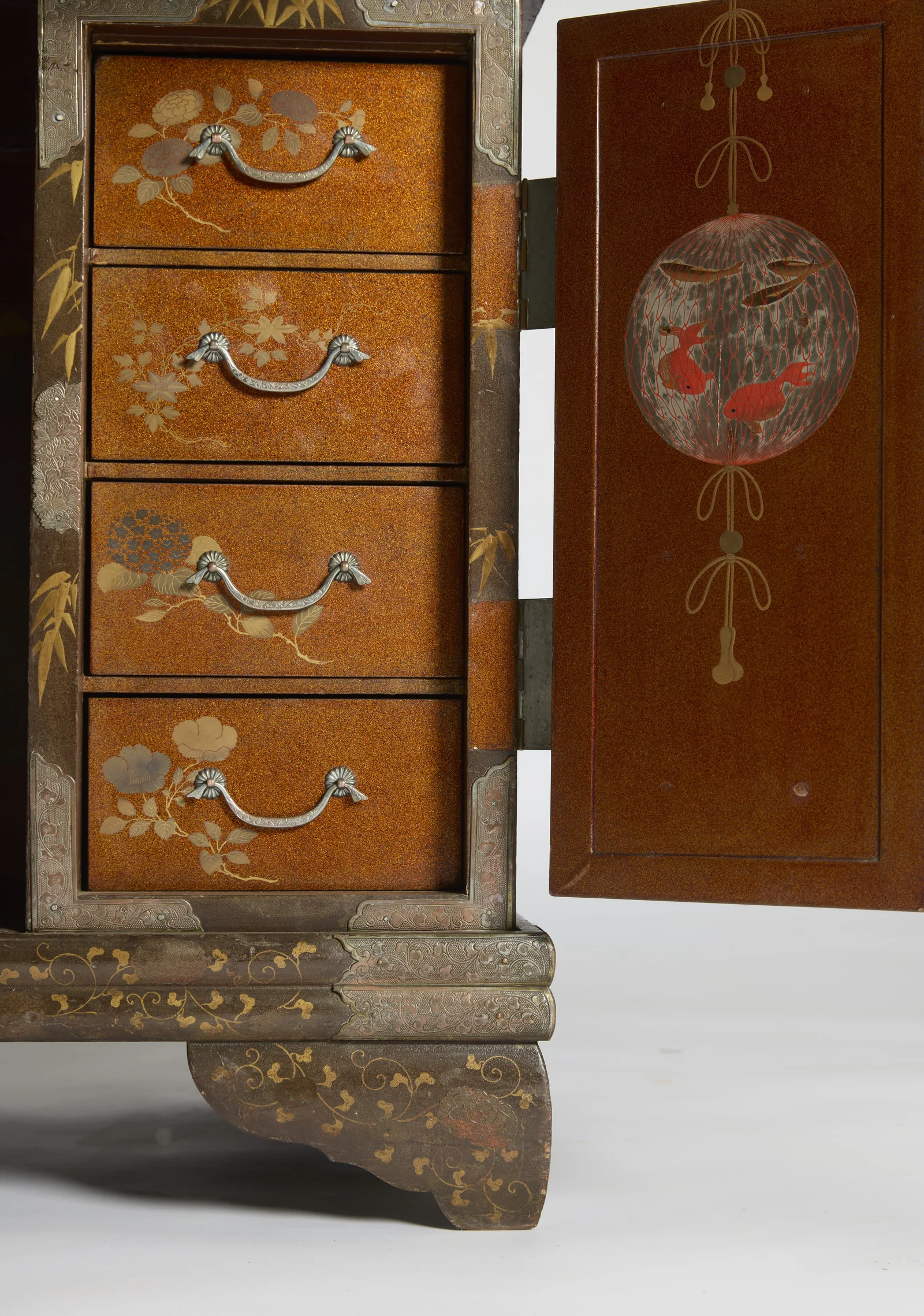 A bank of four flower-decorated drawers beside the open cupboard door, its inner face painted with goldfish caught in a hanging net.
