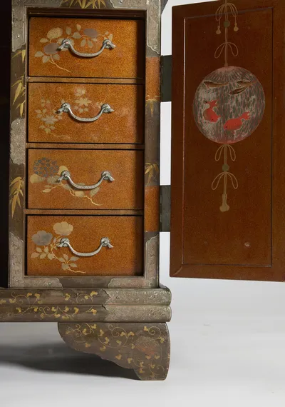 A bank of four flower-decorated drawers beside the open cupboard door, its inner face painted with goldfish caught in a hanging net.