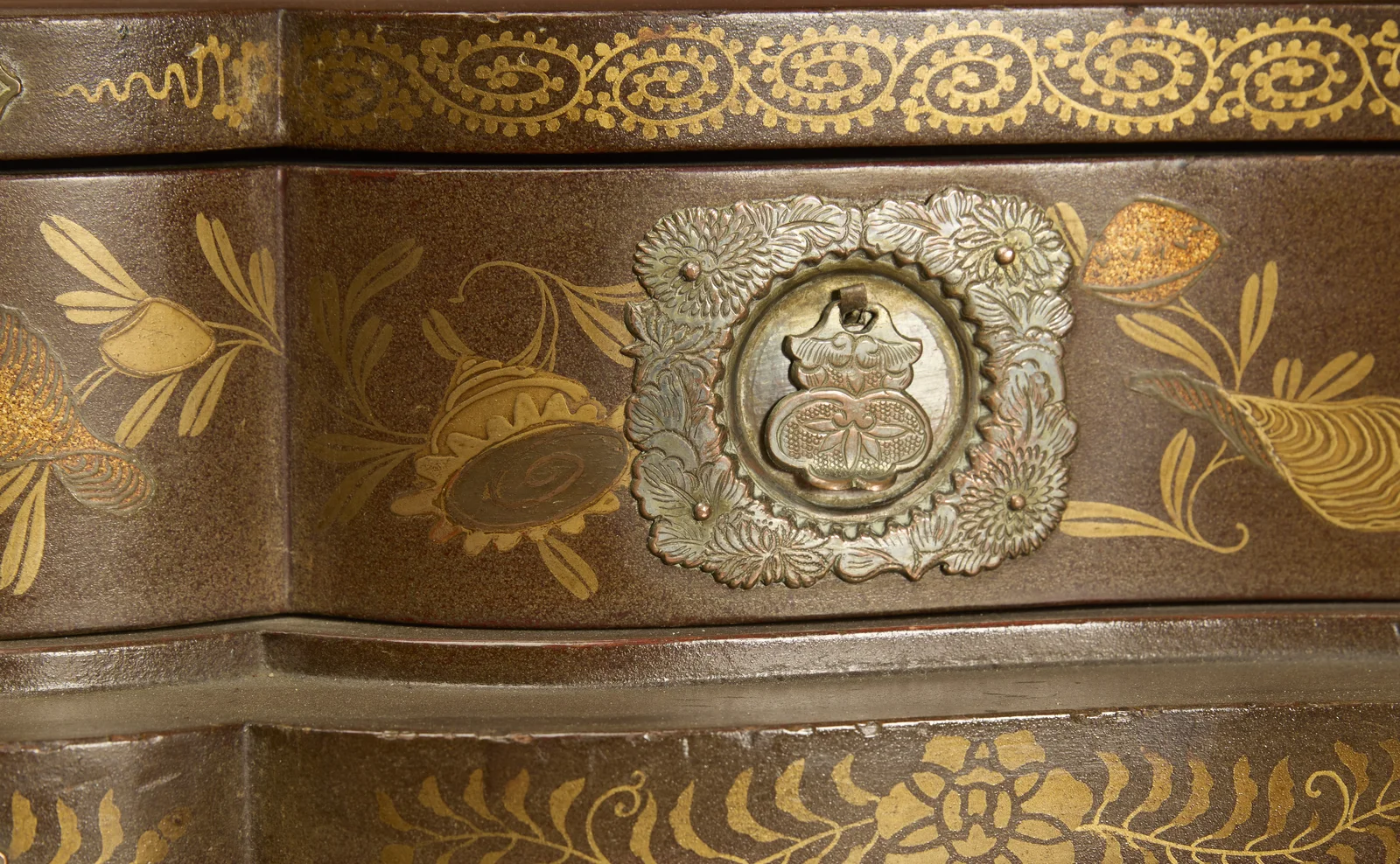 Shells and flowering sprays in gold on the speckled ground, around a pierced and engraved metal plate.