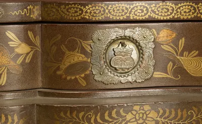 Shells and flowering sprays in gold on the speckled ground, around a pierced and engraved metal plate.