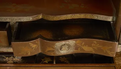 The serpentine drawer pulled open, its interior finished in black with gold speckling, open compartments visible beneath.