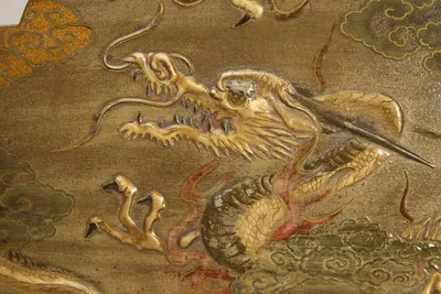 Open jaws, trailing whiskers and scaled coils modelled in relief, with flames picked out in red.