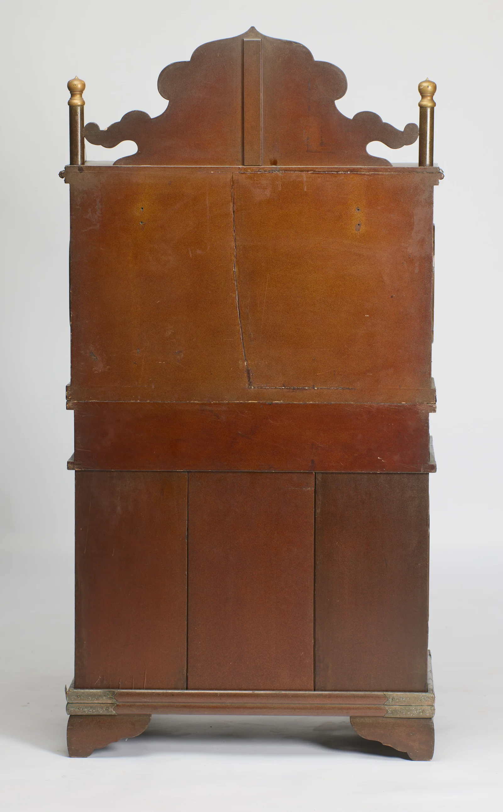 The back finished in plain russet-brown lacquer, showing the crest silhouette, turned finials and metal-bound plinth, with scattered scuffs and scratches.