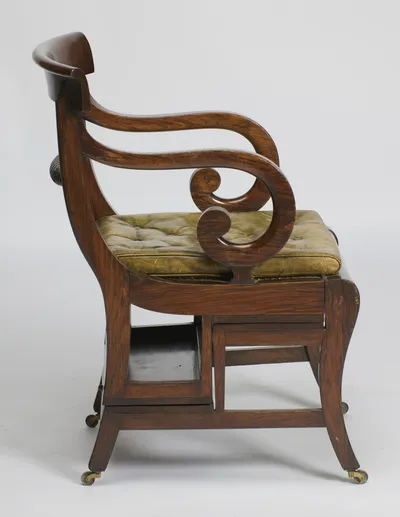 The crest curls over at the rear and the arm sweeps down in a bold double scroll to the seat rail and sabre leg.