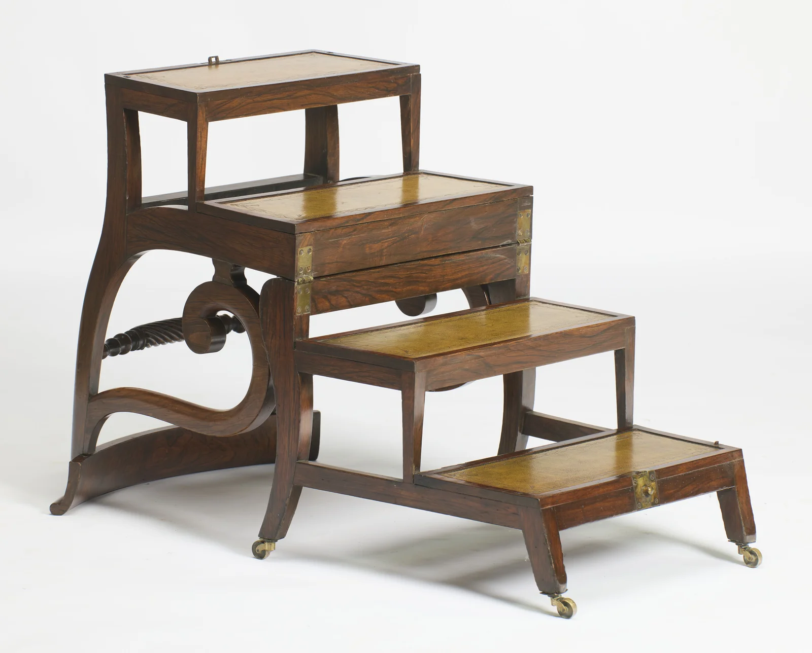 The seat swings over into four treads inset with tooled leather, brass hinge straps at the join and the turned rail showing through the frame.