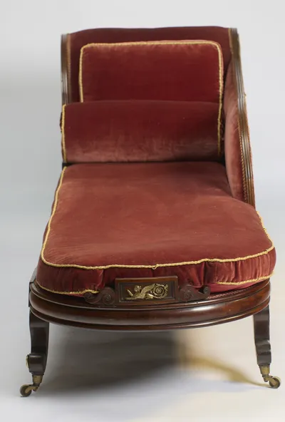 Looking down the length of the seat towards the scrolled end, with a gilt winged-figure panel centred on the moulded seat rail between carved scrolls.