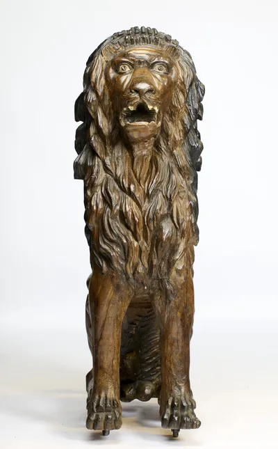 Seen square on, with bared teeth above a carved tongue and metal castors just visible beneath the paws.