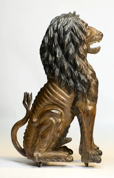 In profile the carving runs from raised muzzle to arched back, the tail curling forward around the haunch.