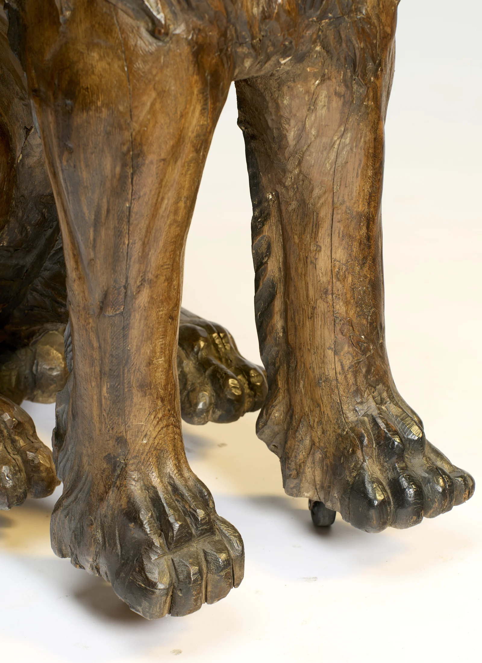 Both forelegs, the toes strongly modelled and dark-tipped, a castor showing beneath the near paw.